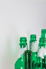 Image of the bottleneck of empty beer and wine green glass bottles on a white background. Reuse, acoholism, recycle and party concept.