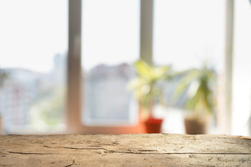 Wood table top on blur of window glass and abstract green from garden with city view in the morning background. For montage product display