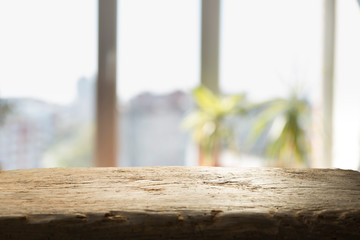 Wood table top on blur of window glass and abstract green from garden with city view in the morning background. For montage product display