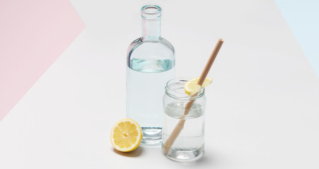 Bamboo straw in a glass of lemon water on the grey background, Reusable bamboo straws as an alternative for single-use plastic straws, healthy and sustainable lifestyle concept