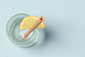 Bamboo straw in a glass of lemon water on the blue background, Reusable bamboo straws as an alternative for single-use plastic straws, healthy and sustainable lifestyle concept