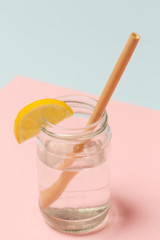 Bamboo straw in a glass of lemon water on the pink background, Reusable bamboo straws as an alternative for single-use plastic straws, healthy and sustainable lifestyle concept
