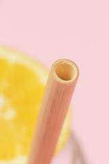 Bamboo straw in a glass of lemon water on the pink background, Reusable bamboo straws as an alternative for single-use plastic straws, healthy and sustainable lifestyle concept