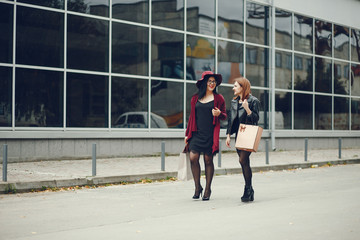 Obraz premium two beautiful and stylish girlfriends walking around the summer city with packages and shopping