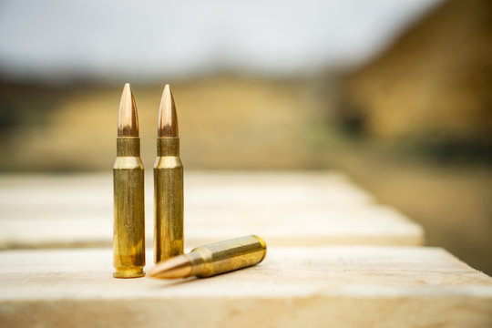 308 caliber ammunition for a rifle standing on a wooden table on the background of the shooting range