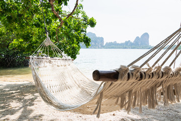 Empty white hammock at Krabi Railey beach overlooking the harbour and mountains, Thailand