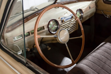 Obraz premium View on opened window with the steering wheel and the interior of the old Russian retro vintage car of the executive class released in the Soviet Union beige