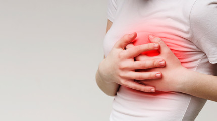 Woman clutching her chest, acute pain as possible heart attack
