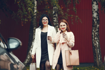 two beautiful and stylish girlfriends walking around the summer city with packages and shopping