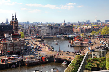 Amsterdam cityscape with Grand Amarath hotel. City streets with active tram and car traffic along the canal. Panoramic distance view. 