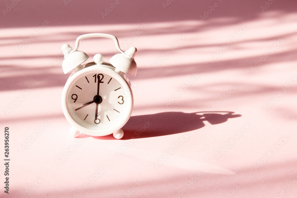 Wall mural Alarm clock on pink background. Morning time background concept