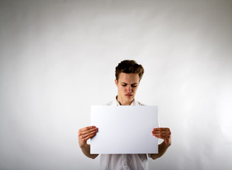 Young man holding white paper in his hands. Unhappy man.