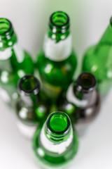 Top view of a pack of blurred  empty green and brownlongneck beer glass bottles, with ripped labels on a white background. Reuse, acoholism, recycle and party concept. Warm tones.
