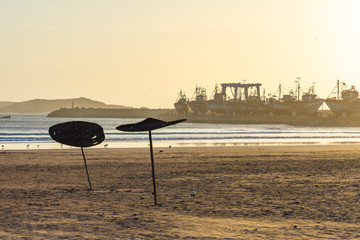 Sunset on the Beach in Essaouira Morocco with a view of the Harbor and Umbrellas