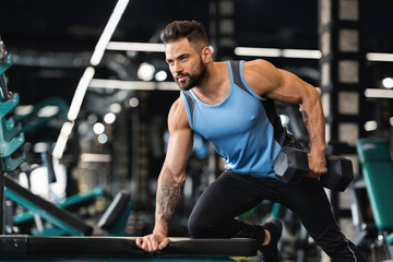 Fototapeta na wymiar Millennial muscular man doing exercises with dumbbells