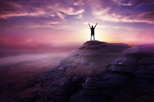 A man expressing freedom by reaching up to the sky as the sun sets in the distance. Hopes and dreams photo composite.