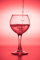 Flowing  liquid (wine) in a glass on a red background