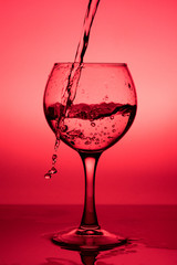 Flowing  liquid (wine) in a glass on a red background