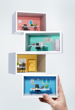 Work and business concept. A person holding a stack of individual miniature business office rooms. 3D illustration.