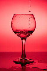 Flowing  liquid (wine) in a glass on a red background