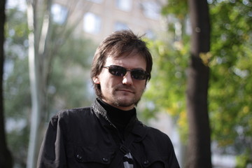 a man in a black jacket and sunglasses in the park