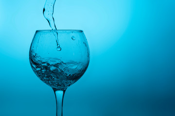 Wine glass with liquid (white wine) on a blue background
