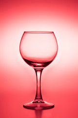 Wine glass with liquid (white wine) on a red background