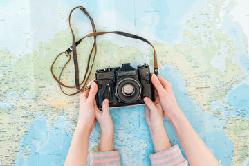 Cropped view of woman and kid holding film camera on world map