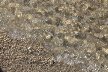 Close up of bubbly, glassy water at beach