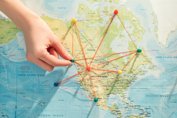 Partial view of woman with push pins, strings and world map
