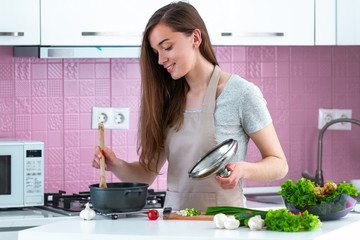 Woman in apron cooking dinner from fresh ripe vegetables at home in the kitchen. Clean food and...
