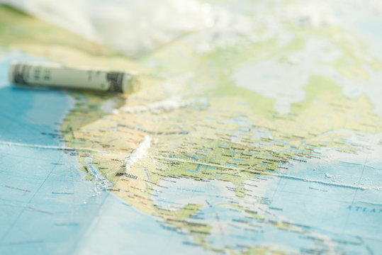 Selective focus of cocaine and dollar banknote on world map