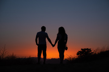 Fototapeta na wymiar Young couple enjoying sunset in the mountains