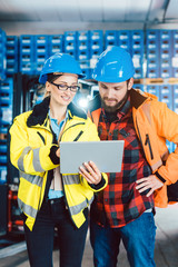 Woman and man as workers in logistics center using computer