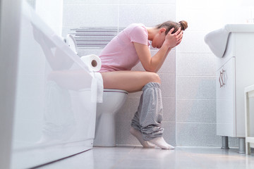 Ill, unwell woman suffering from diarrhea, constipation and stomach pain at toilet. Health care - obrazy, fototapety, plakaty