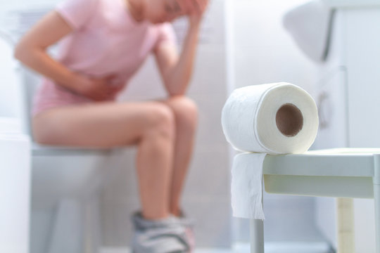 Ill, unwell woman suffering from diarrhea, constipation and cystitis at toilet. Stomach pain during PMS. Health care and pain concept
