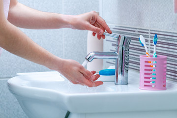Washing hands under faucet with water in bathroom. Hygiene and hand care