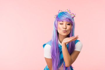Asian anime girl sending air kiss and winking isolated on pink