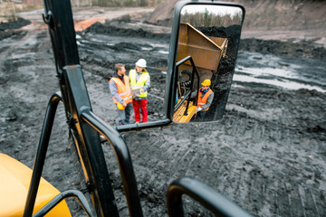 Workers in quarry seen in the mirror of a heavy-duty truck