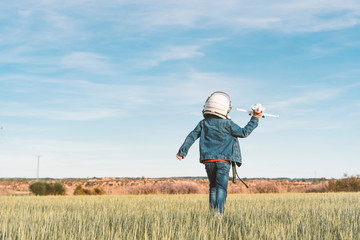 Kid playing with plane toy dressed as astronaut