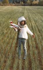 Kid playing with plane toy dressed as astronaut