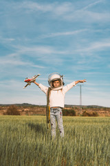 Kid playing with plane toy dressed as astronaut