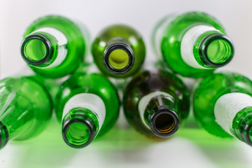 Top view of a pack of empty beer and wine green and brown glass bottles, with ripped labels on a white background. Reuse, acoholism, recycle and party concept.