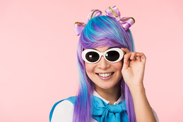 Smiling anime girl in wig and sunglasses isolated on pink