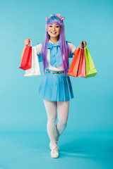 Full length view of asian anime girl holding shopping bags on blue