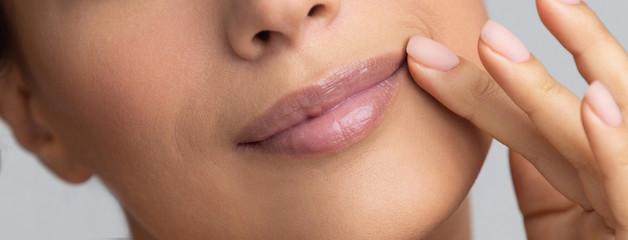 African-american girl holding hand near lips, grey background
