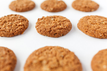Freshly baked oatmeal raisin cookies on cooling rack over rustic wood background. Closeup from above with natural directional lighting