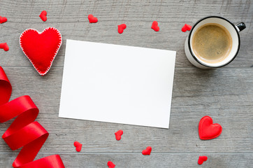 Mockup blank romantic postcard with felt hearts, red ribbon and coffee mug. Top view workspace flat lay