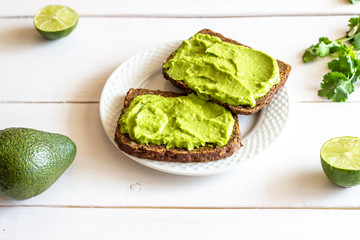 Sandwiches with avocado on the white wooden background.