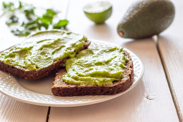 Sandwiches with avocado on the white wooden background.